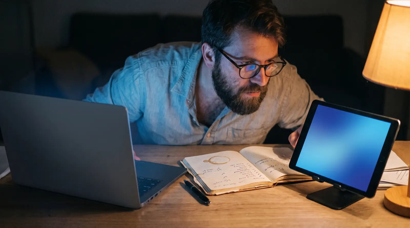 Man vergelijkt IPTV-aanbieders op een laptop en tablet met handgeschreven aantekeningen